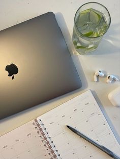 an apple laptop computer sitting on top of a desk next to a notepad and pen