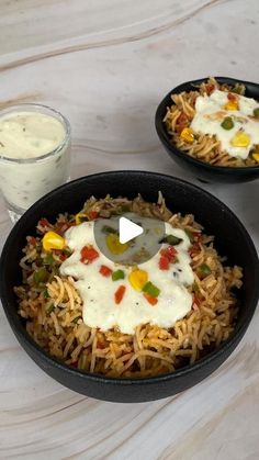 two black bowls filled with rice and veggies next to a glass of milk