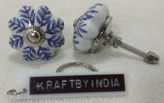 two blue and white ceramic knobs with name tag attached to them on a white cloth