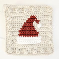 a crocheted square with a red and white santa hat on it's side