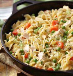 a skillet filled with pasta, peas and chicken