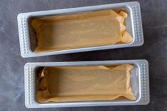 two white trays filled with food sitting on top of a gray countertop next to each other