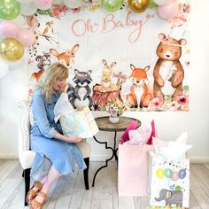 a woman sitting on a chair in front of a wall with balloons and stuffed animals