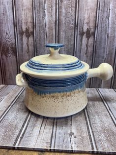 a blue and white casserole sitting on top of a wooden table next to a wall