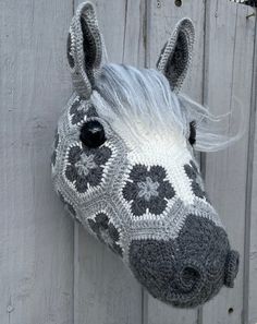 a crocheted horse's head hanging on the side of a wooden fence