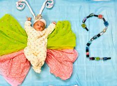 a baby laying on top of a blanket next to beads and necklaces in the shape of a butterfly