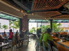 people sitting at tables in a restaurant with lots of windows looking out onto the ocean