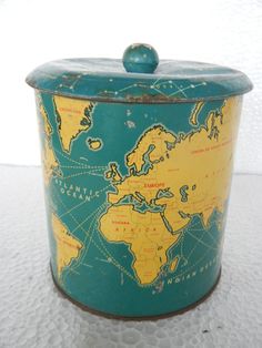 a blue and yellow tin with a world map on the lid sitting on a white surface