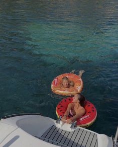 two people floating on inflatable rafts near the water