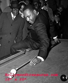 a man in a suit leaning over a pool table to hit a ball with a cue