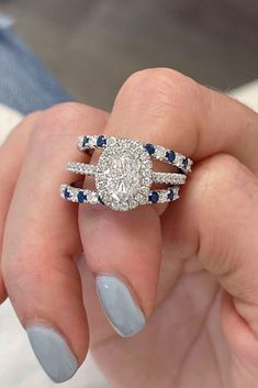 a woman's hand holding an engagement ring with blue and white stones on it