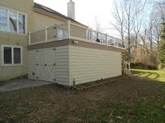 a house with a deck on the side of it and an attached garage in front