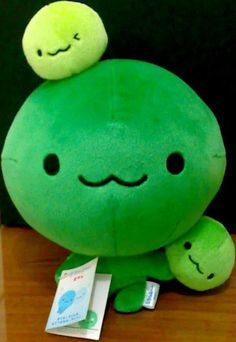 a green stuffed animal sitting on top of a wooden table