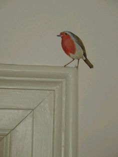 a small bird sitting on top of a white door frame in front of a wall