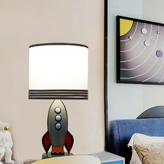 a lamp that is sitting on top of a table next to a bed with pillows