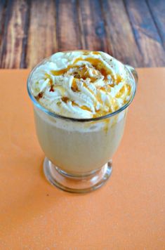 a dessert with whipped cream and nuts in a glass bowl on an orange place mat