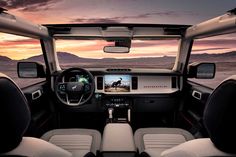 the interior of a truck with dashboard, steering wheel and dash lights on at sunset