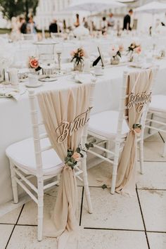 two white chairs sitting next to each other on top of a floor covered in table cloths