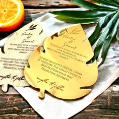 two wooden tags with writing on them sitting next to an orange and palm tree branch