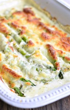 a casserole dish with broccoli and cheese in it on a wooden table