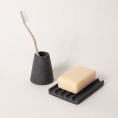 a toothbrush and soap in a holder on a white surface with a gray background