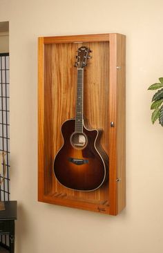 an acoustic guitar mounted to the wall in a wooden case with a mirror on it