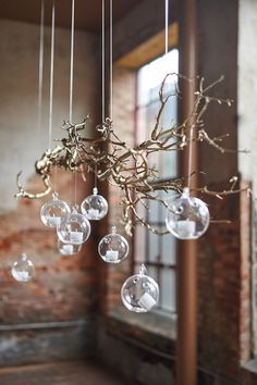 a chandelier with glass balls hanging from it's branches in front of a window