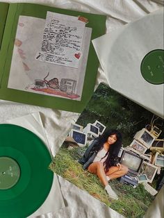 two green records sitting on top of a bed next to papers and pictures in folders