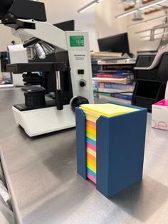 a stack of colored post it notes sitting on top of a table next to a printer