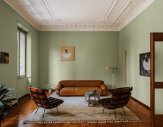 a living room with green walls and wooden furniture in the center, along with a rug on the floor