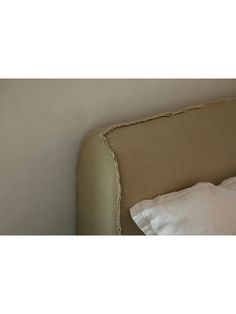 an upholstered headboard with white pillows and linens on the bottom half