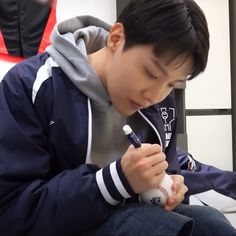 a young man sitting down holding a baseball bat