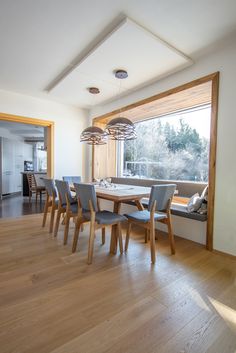 a dining room table and chairs in front of a large window with wooden flooring