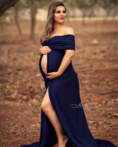 a pregnant woman in a blue dress poses for a photo with her belly exposed and legs crossed