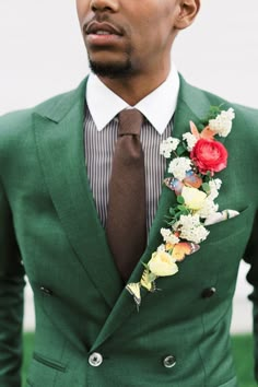 a man in a green suit with flowers on his lapel