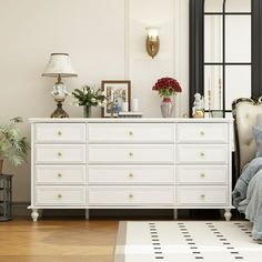 a white dresser sitting next to a bed in a bedroom