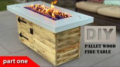 the diy pallet wood fire table is made from an old crate and has flames burning