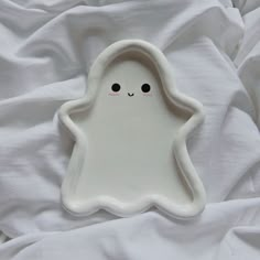 a white plate with a little ghost on it's side, sitting on a bed