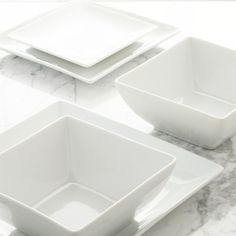 three white square dishes sitting on top of a marble counter