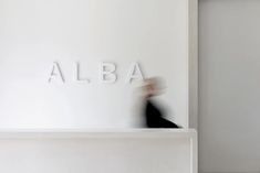 blurry photograph of the word alba in front of a white wall with letters on it