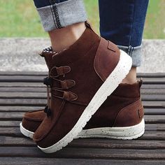 a person standing on top of a wooden bench wearing brown shoes and jeans with white laces