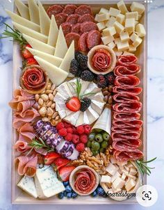 an assortment of cheeses, meats and vegetables on a platter with fruit