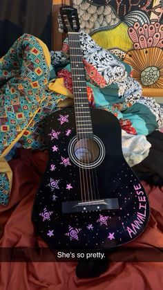 a guitar sitting on top of a bed next to a pillow and quilted blanket