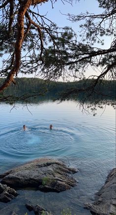 two people are swimming in the water near some rocks