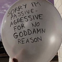 a person holding a white balloon with writing on it that says sorry i'm passive aggressive for no god damn reason