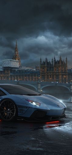 a blue sports car is parked in front of the big ben clock tower at night