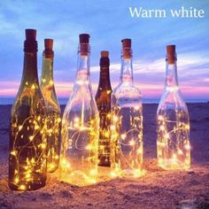 bottles with lights in them sitting on the beach