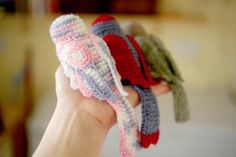 a person holding three knitted mittens in their hands