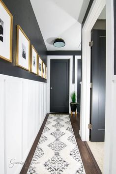 the hallway is decorated in black and white with pictures on the wall, along with a rug