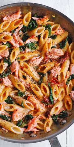 pasta with ham and spinach in a skillet on a white wooden table top